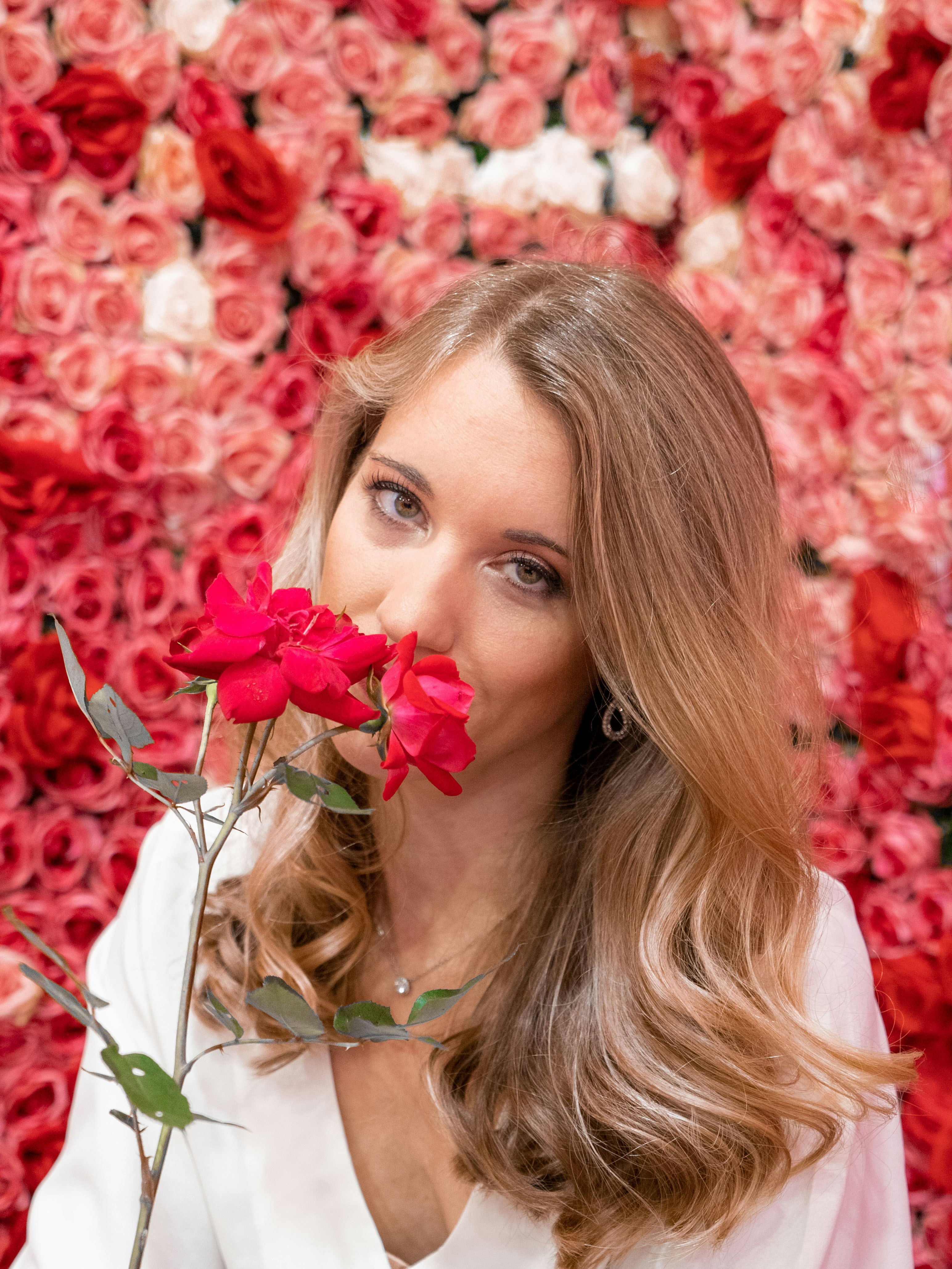 woman in white dress holding red flowers